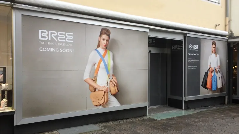 werbliche schaufensterbeschriftung an modegeschaeft mit markenmotiv